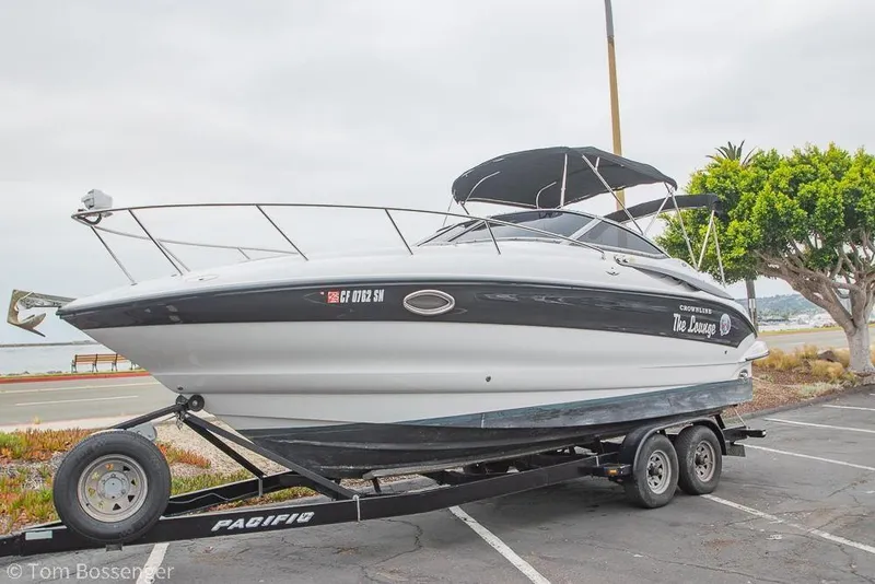 Slide: The Image of 2004 Crownline 250 CR boat on trailer, parked near waterfront, overcast sky. - 57