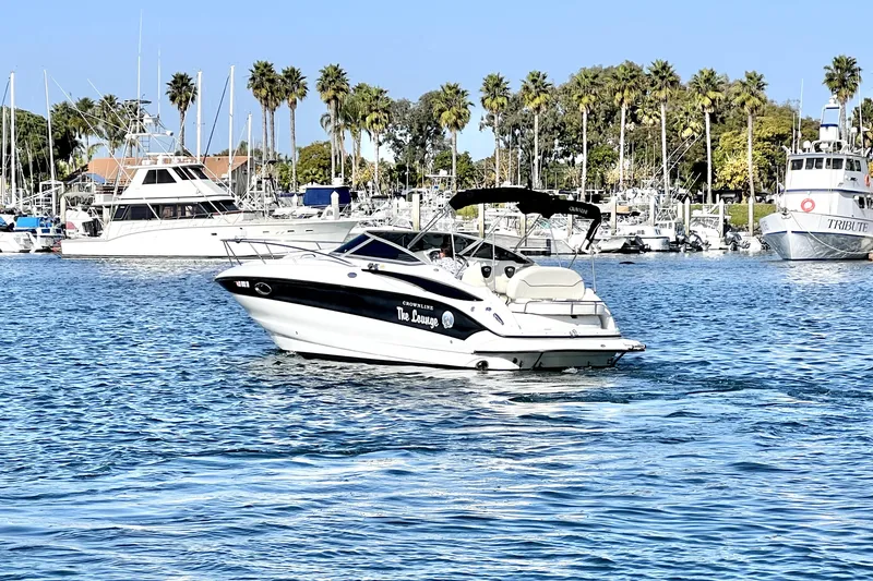 Slide: The Image of 2004 Crownline 250 CR boat cruising in a marina with palm trees and yachts. - 7