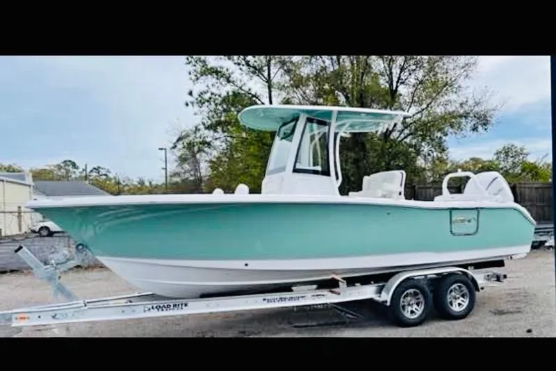 The Image of 2023 Sea Hunt Ultra 255 SE boat on trailer, light blue hull, parked outdoors. - 0