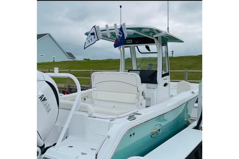 Slide: The Image of 2023 Sea Hunt Ultra 255 SE boat with flags, docked under cloudy skies. - 19