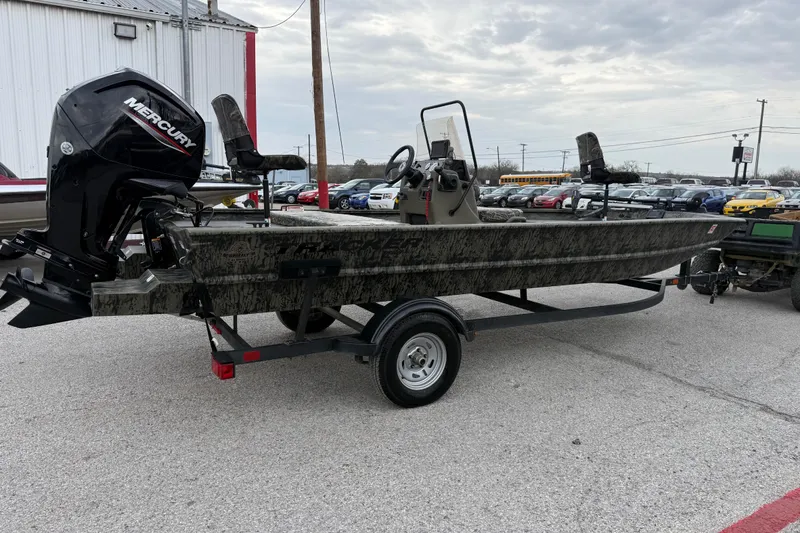 Slide: The Image of 2025 Tracker Grizzly 1860 MVX CC boat with camo seats and console, parked outdoors. - 17