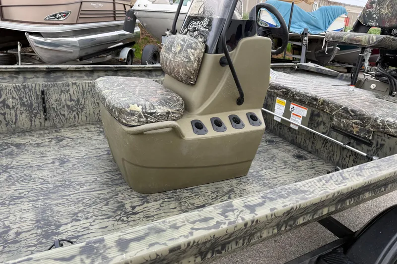 Slide: The Image of 2025 Tracker Grizzly 1860 MVX CC boat interior with steering console and camo seating. - 31