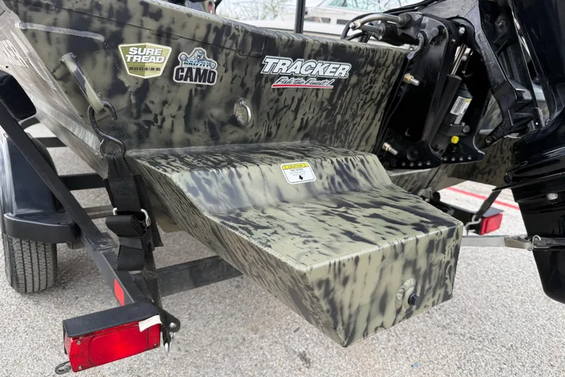 Slide: The Image of 2025 Tracker Grizzly 1860 MVX CC boat with camouflage seats, parked among other boats. - 35
