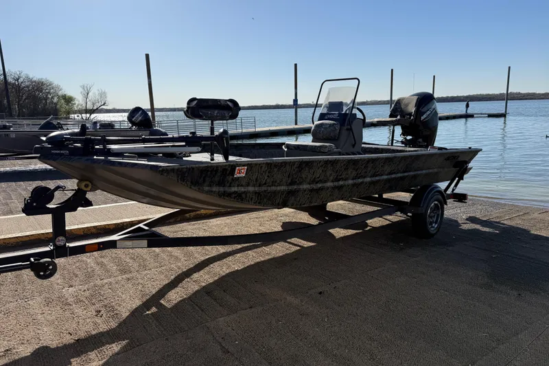 Slide: The Image of 2025 Tracker Grizzly 1860 MVX CC boat on trailer by a lakeside dock. - 54