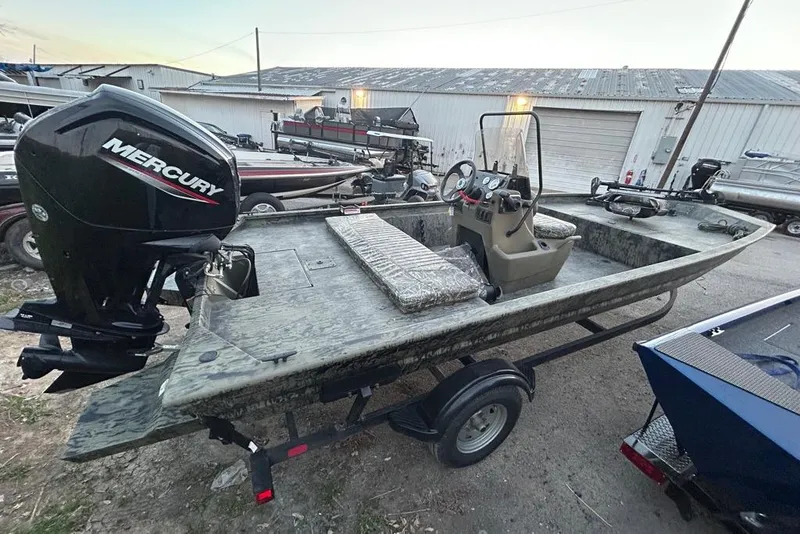 Slide: The Image of 2025 Tracker Grizzly 1860 MVX CC boat with outboard motor, parked in a lot. - 6