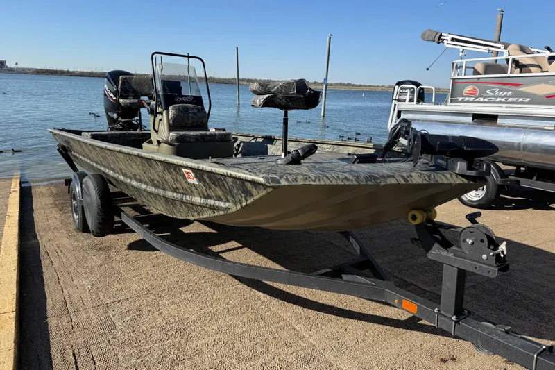 Slide: The Image of 2025 Tracker Grizzly 1860 MVX CC boat on trailer by a lake. - 62