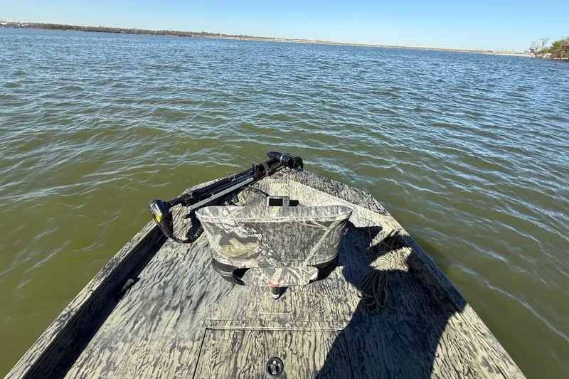 Slide: The Image of 2025 Tracker Grizzly 1860 MVX CC boat on calm lake waters under clear blue sky. - 73