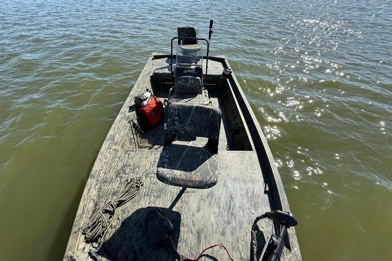 Slide: The Image of 2025 Tracker Grizzly 1860 MVX CC boat on water, featuring camouflage design and fishing gear. - 74