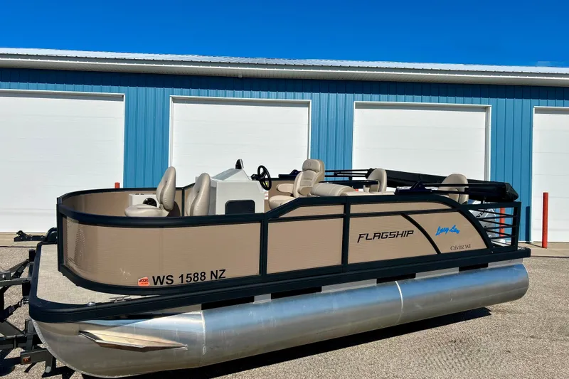 Slide: The Image of 2023 Flagship 200 Lounge Lounger pontoon boat parked near blue building. - 3