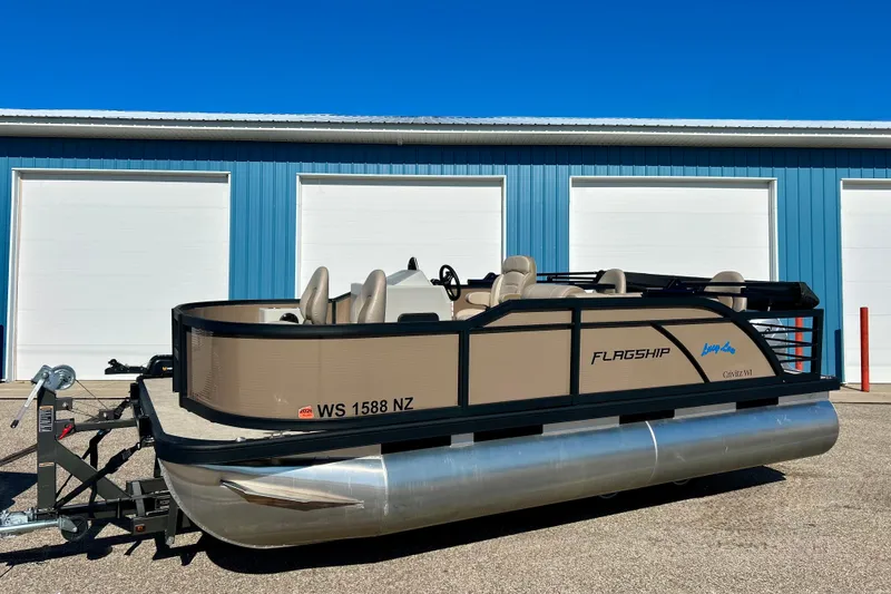 Slide: The Image of 2023 Flagship 200 Lounge Lounger pontoon boat parked outside blue garage. - 44