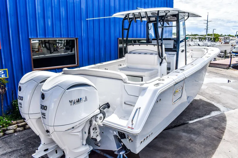 Slide: The Image of 2026 Sea Hunt Ultra 285 Coffin Box boat with twin Yamaha engines, docked near a blue building. - 12