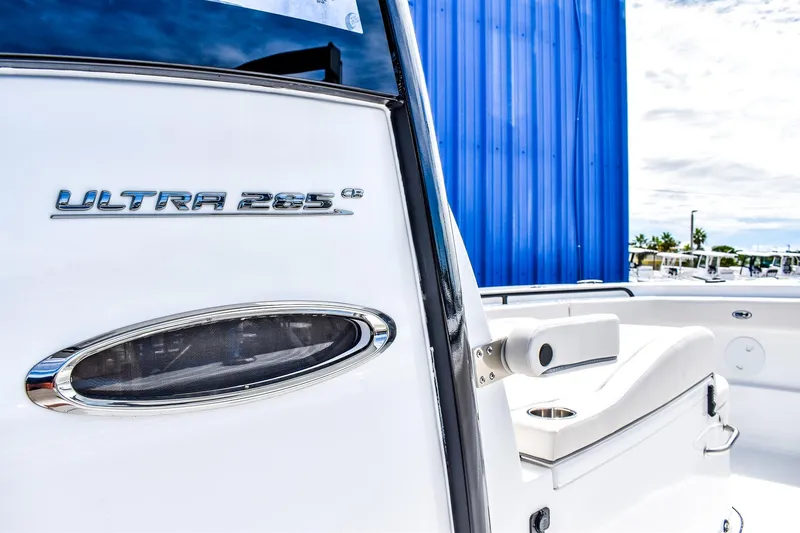 Slide: The Image of 2026 Sea Hunt Ultra 285 Coffin Box boat, sleek design with white seating and blue backdrop. - 9