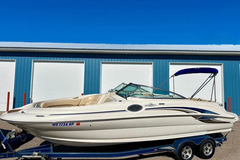 Slide: The Image of 2000 Sea Ray 240 Sundeck boat on trailer, parked outside blue building. - 3