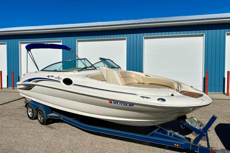 Slide: The Image of 2000 Sea Ray 240 Sundeck boat on trailer, parked in front of blue storage units. - 4