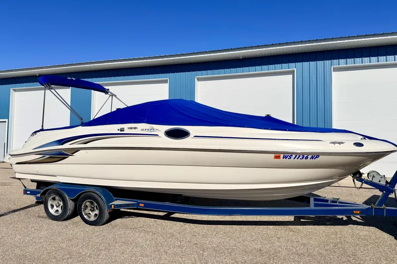 Slide: The Image of 2000 Sea Ray 240 Sundeck boat on trailer, blue cover, parked by blue building. - 63
