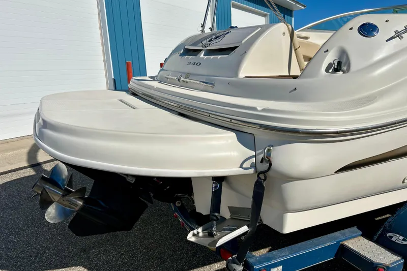 Slide: The Image of 2000 Sea Ray 240 Sundeck boat on trailer, parked near blue building. - 9