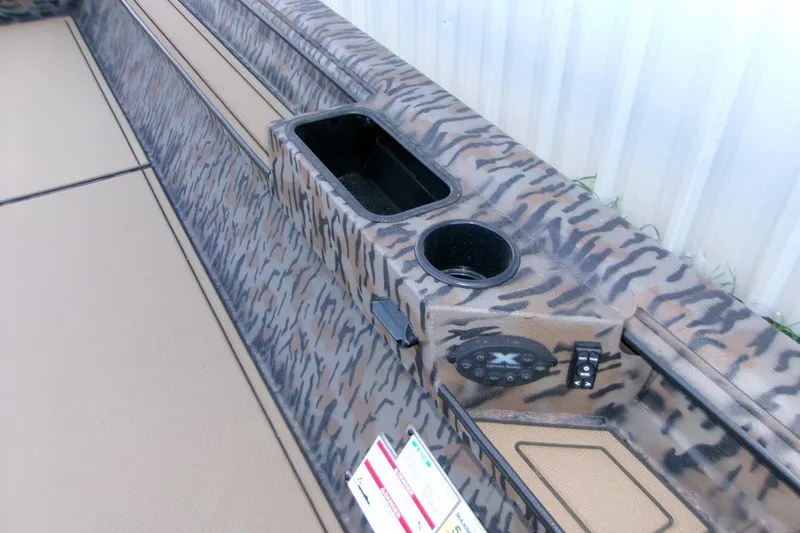 Slide: The Image of 2026 Xpress X18DB boat interior with camo design, featuring cup holder and control panel. - 12