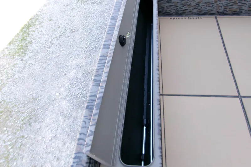 Slide: The Image of 2026 Xpress X18DB boat storage compartment with camouflage trim and beige interior. - 18