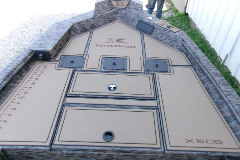 Slide: The Image of 2026 Xpress X18DB boat deck with storage compartments and measuring ruler. - 8