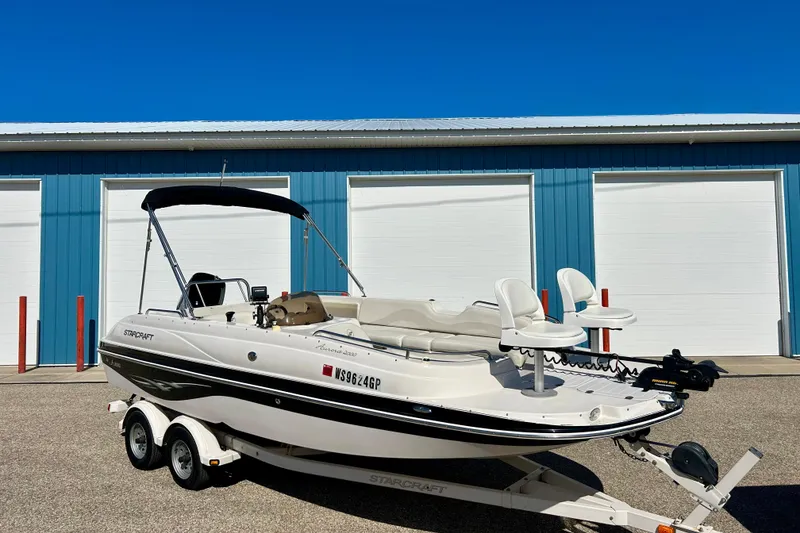 Slide: The Image of 2004 Starcraft Aurora 2000 OB boat on trailer, parked in front of blue storage units. - 2