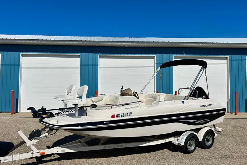 Slide: The Image of 2004 Starcraft Aurora 2000 OB boat on trailer, parked in front of blue storage units. - 3