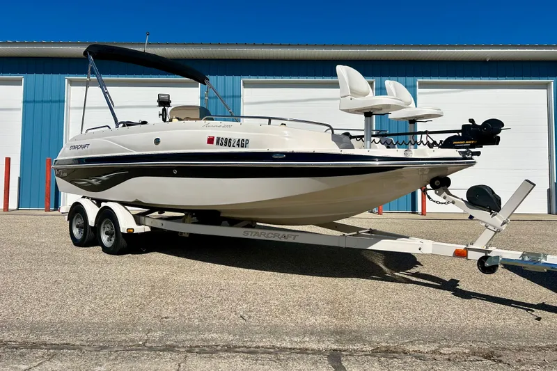 Slide: The Image of 2004 Starcraft Aurora 2000 OB boat on trailer, parked outside blue building. - 4