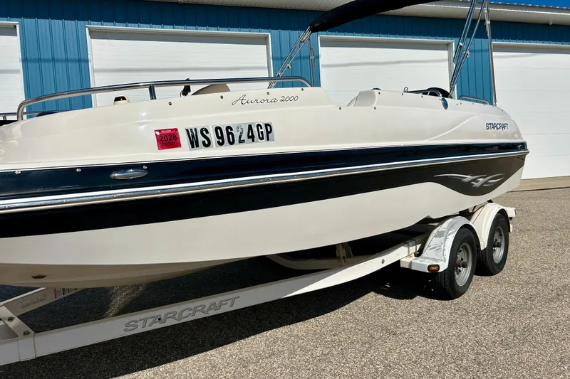 Slide: The Image of 2004 Starcraft Aurora 2000 OB boat on trailer, parked near blue building. - 42