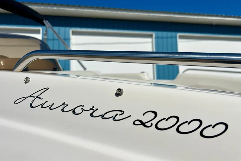 Slide: The Image of 2004 Starcraft Aurora 2000 OB boat with elegant script, blue building background. - 5