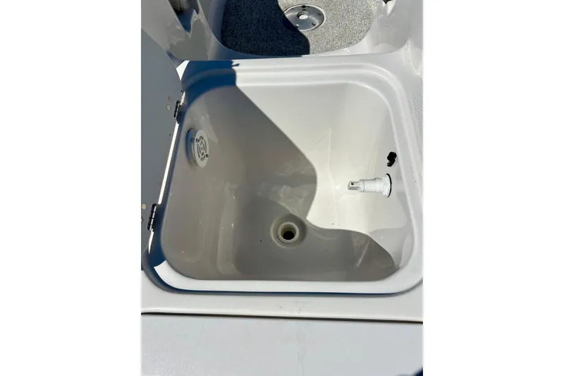 Slide: The Image of 2004 Starcraft Aurora 2000 OB boat livewell, open and empty, with visible drain and fittings. - 51
