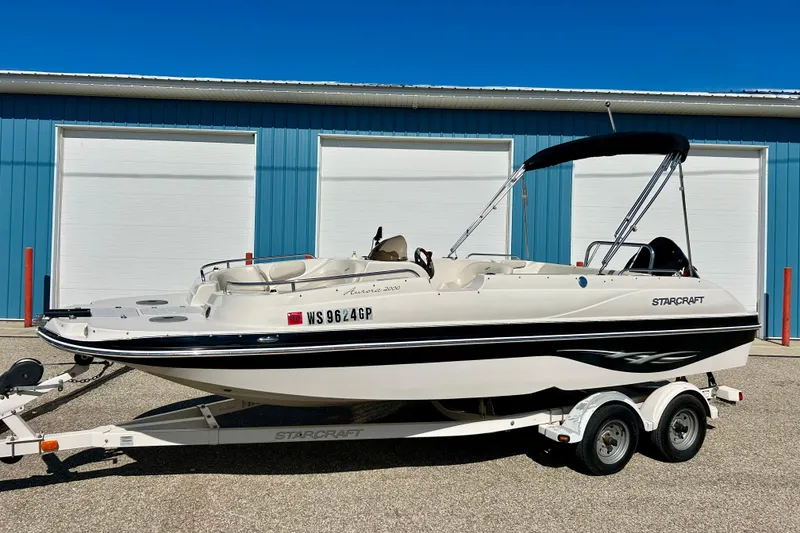 Slide: The Image of 2004 Starcraft Aurora 2000 OB boat on trailer, parked near blue building. - 55