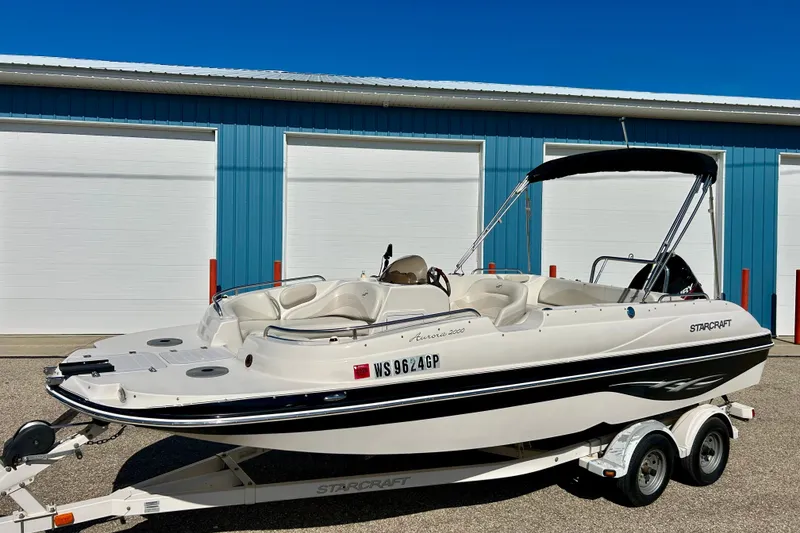 Slide: The Image of 2004 Starcraft Aurora 2000 OB boat on trailer, parked near blue building. - 57