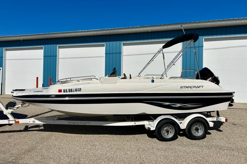 Slide: The Image of 2004 Starcraft Aurora 2000 OB boat on trailer, parked outside blue building. - 58