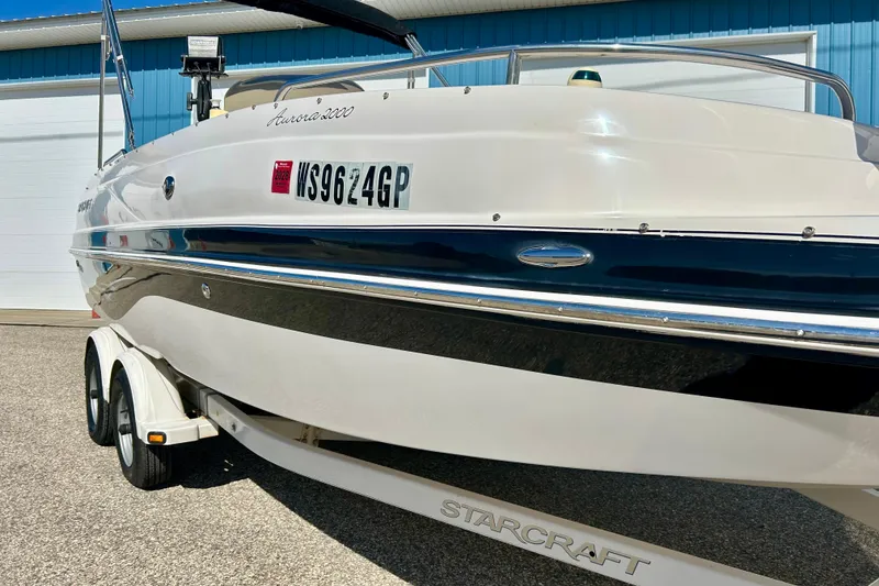 Slide: The Image of 2004 Starcraft Aurora 2000 OB boat on trailer, parked near blue building. - 6