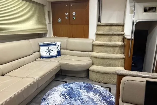 Slide: The Image of 1999 Maxum 4100 SCA yacht interior with beige seating, nautical decor, and carpeted stairs. - 5