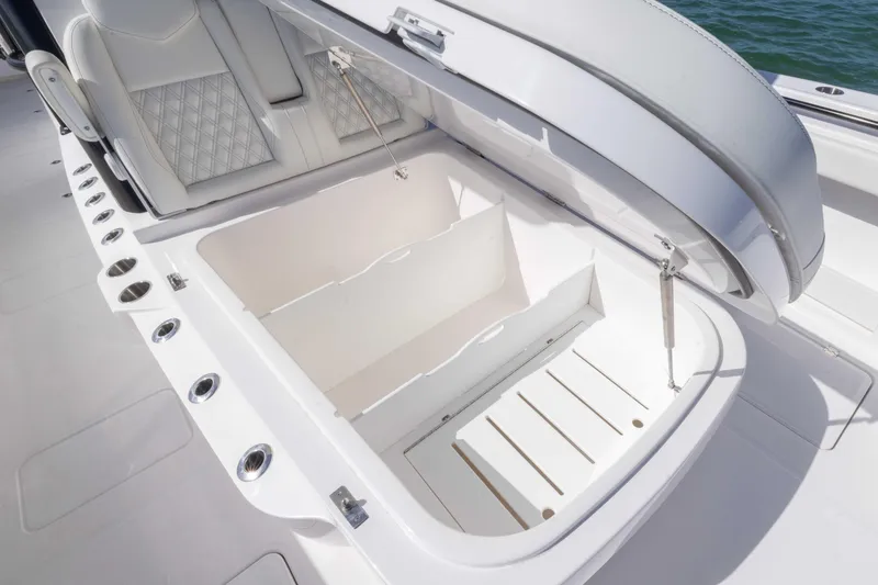 Slide: The Image of 2025 Invincible 35 Catamaran storage compartment with cushioned seating and rod holders. - 11