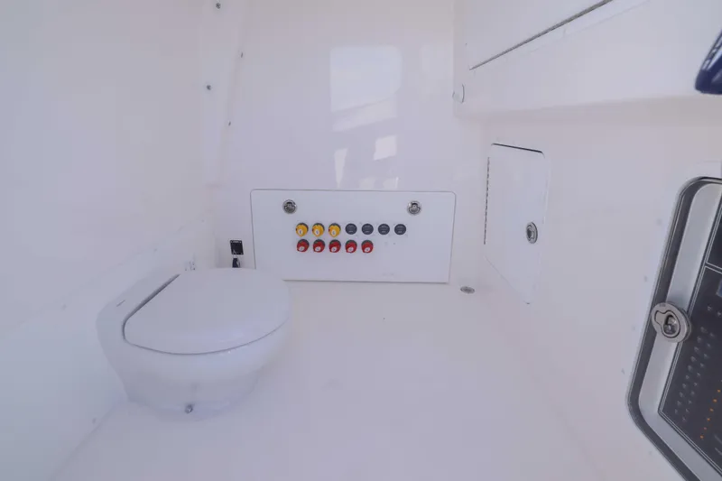 Slide: The Image of Interior of 2025 Invincible 35 Catamaran featuring a compact marine toilet and control panel. - 16