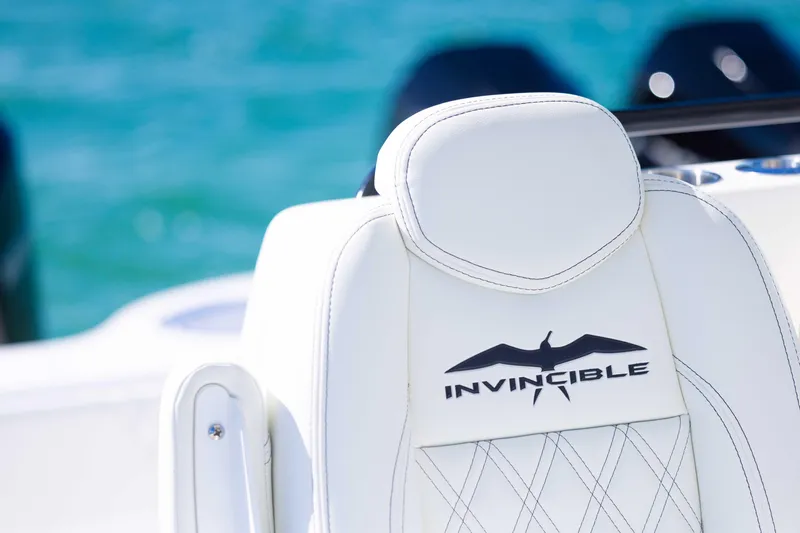 Slide: The Image of White leather seat on 2025 Invincible 35 Catamaran, featuring logo and ocean backdrop. - 33