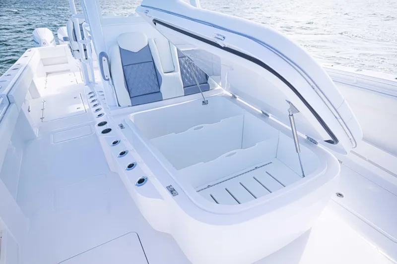 Slide: The Image of 2025 Invincible 35 Catamaran with open storage compartment, sleek seating, and ocean backdrop. - 12