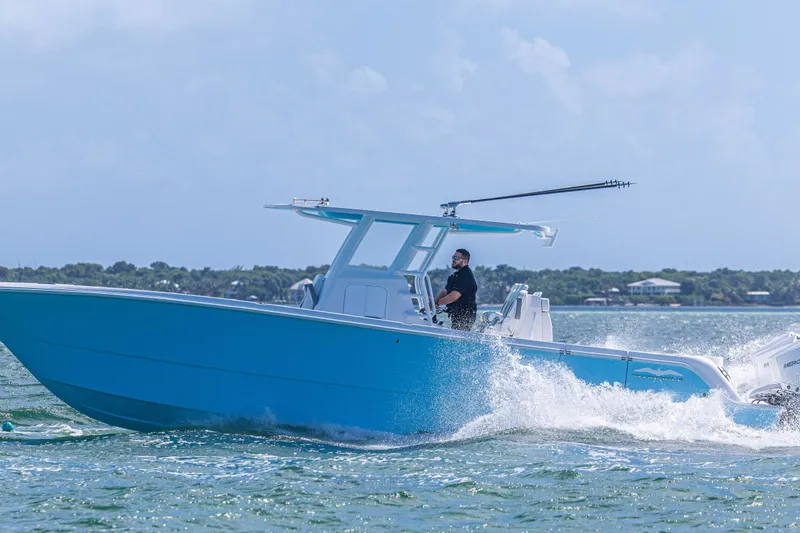 Slide: The Image of 2025 Invincible 35 Catamaran cruising on water, featuring sleek blue design and powerful engines. - 36