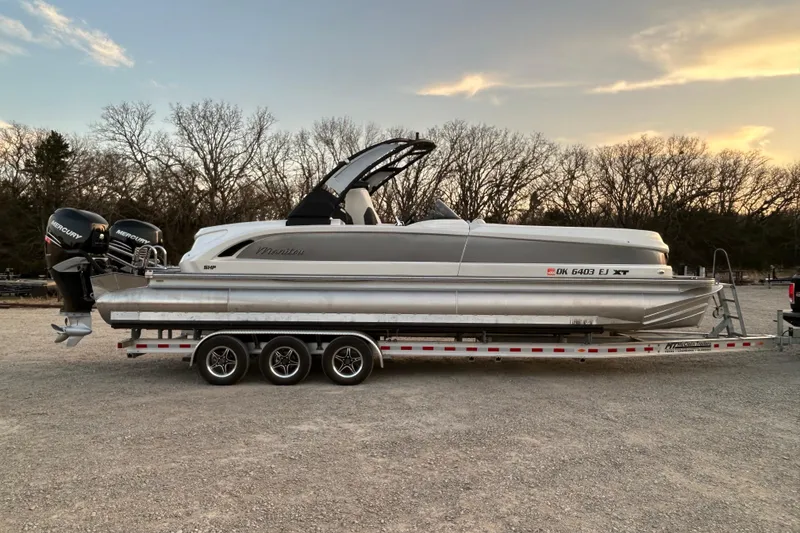 The Image of 2023 Manitou 270 pontoon boat on trailer, featuring dual Mercury engines. - 0