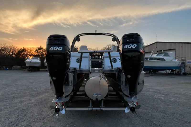 Slide: The Image of 2023 Manitou 270 boat with dual 400 Verado engines at sunset in a boatyard. - 18