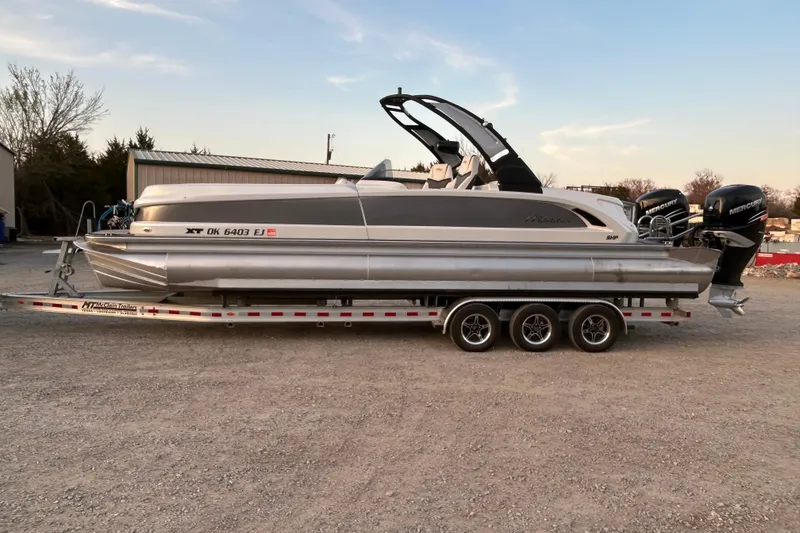 Slide: The Image of 2023 Manitou 270 pontoon boat on trailer, featuring dual Mercury engines. - 2