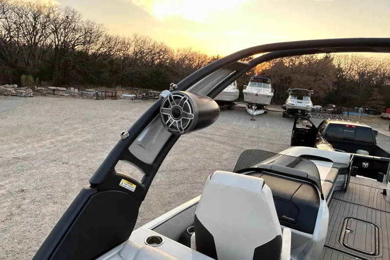 Slide: The Image of 2023 Manitou 270 boat interior with speaker, parked near other boats at sunset. - 22