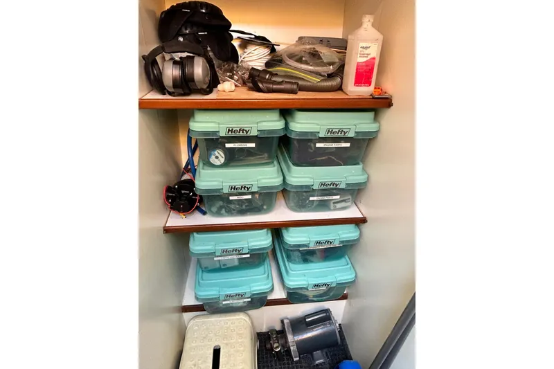 Slide: The Image of Storage shelves with labeled Hefty bins, headphones, and cleaning supplies on a Jefferson 52 Rivanna Cockpit MY. - 51