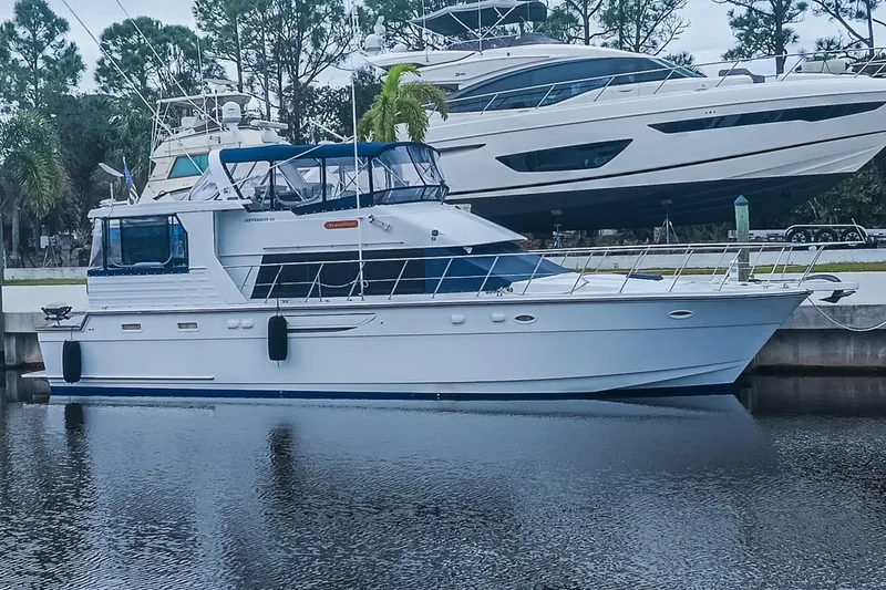 Slide: The Image of 1996 Jefferson 52 Rivanna Cockpit MY yacht docked by the water, surrounded by trees. - 77