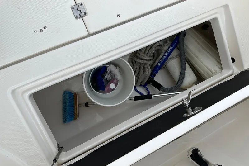 Slide: The Image of Storage compartment of 2007 Robalo R305 Walkaround boat with cleaning supplies and rope. - 16