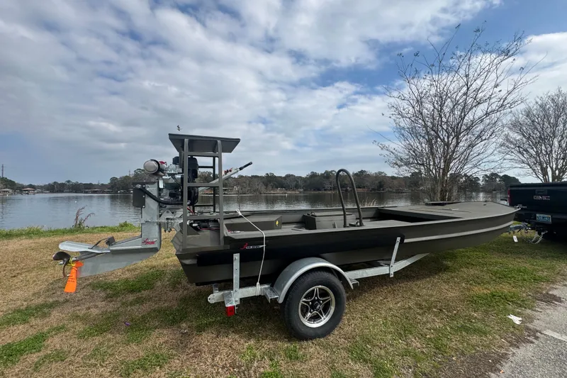 The Image of 2026 Go-Devil 18×60 Surface Drive boat on trailer by a lake. - 0