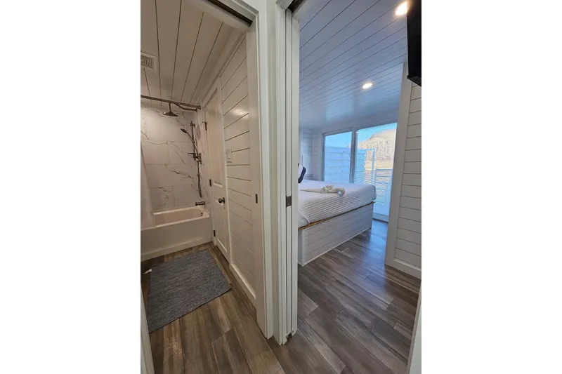 Slide: The Image of Modern 2025 houseboat interior with bathroom and bedroom, featuring sleek wood flooring and white paneling. - 14