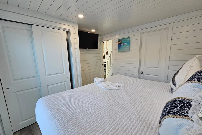 Slide: The Image of Modern 2025 houseboat bedroom with white decor, cozy bed, and wall-mounted TV. - 16