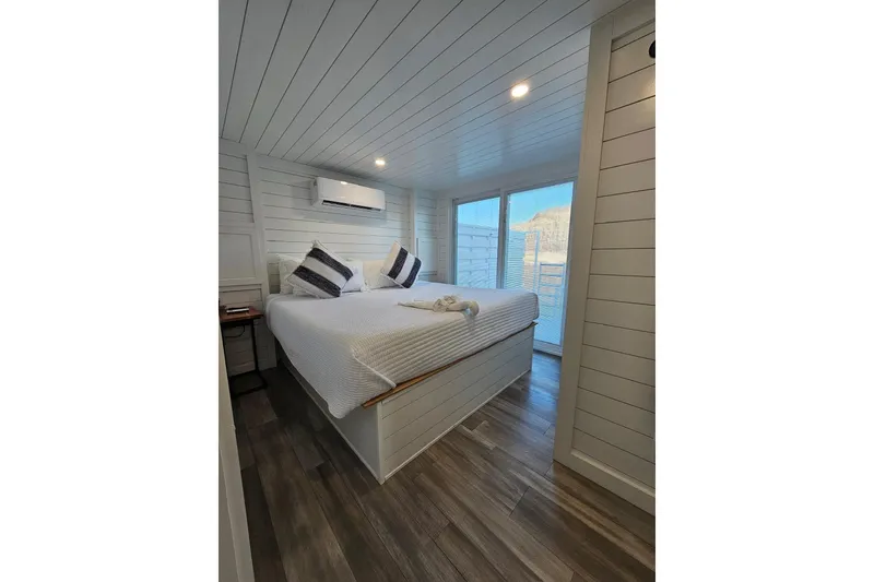 Slide: The Image of Modern 2025 houseboat bedroom with white decor, large bed, and natural light. - 19